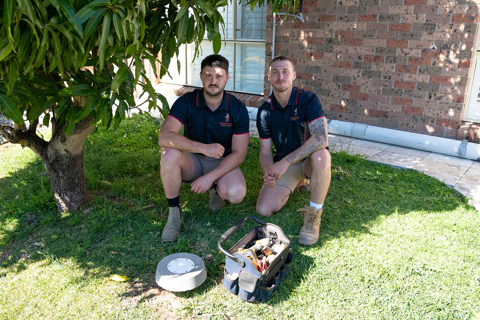 Two Fixed Today plumbers with drain gear on a Sydney lawn
